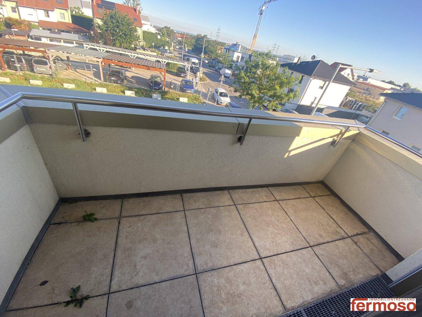 Geräumiger Balkon mit Fliesenboden und Blick auf die Nachbarschaft.