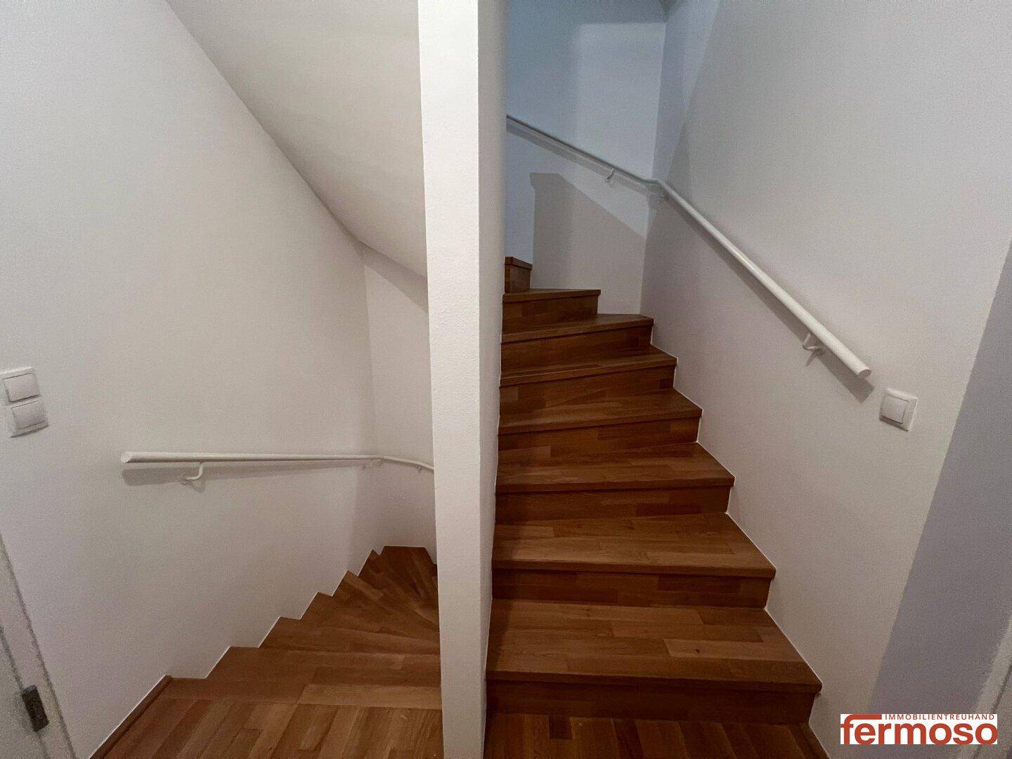 Holztreppe mit Geländer, die verschiedene Ebenen der Wohnung miteinander verbindet.