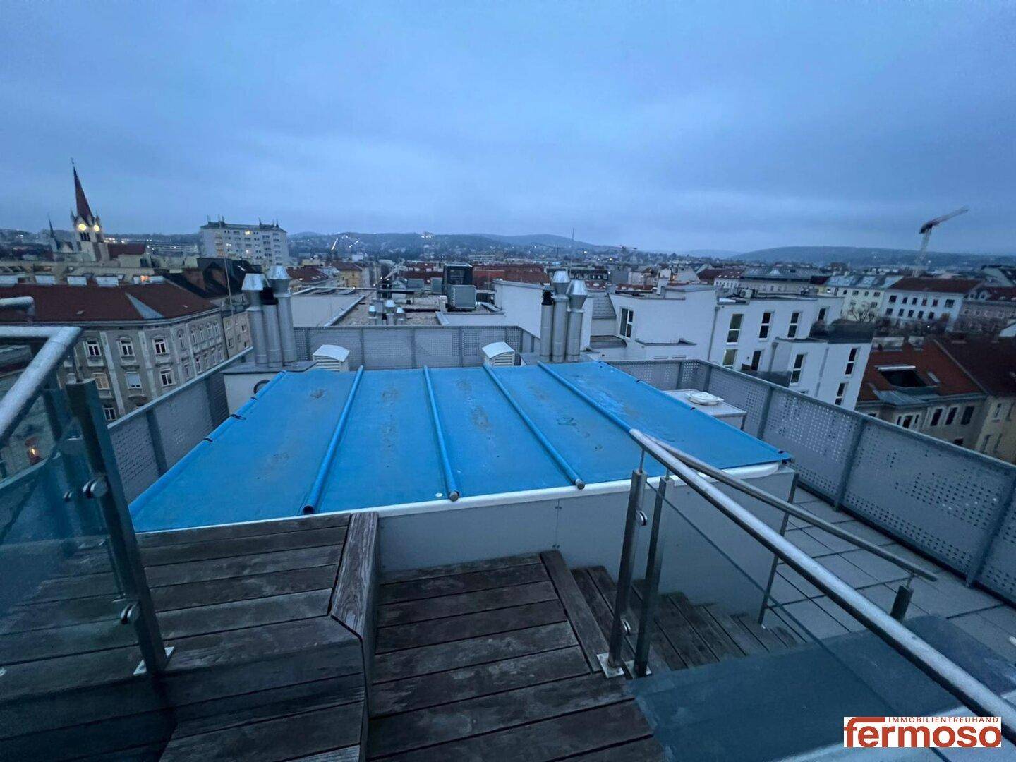 Dachterrasse mit Poolabdeckung und weitem Blick über die Stadtlandschaft.
