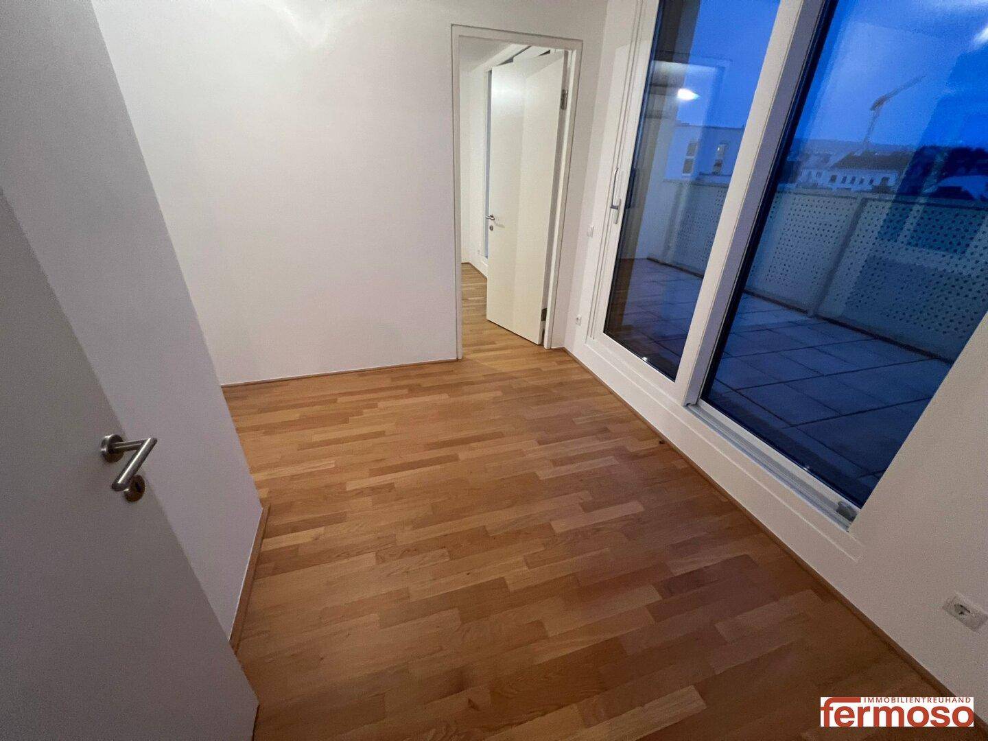 Helles Schlafzimmer mit Parkettboden und direktem Zugang zu einem Außenbereich.