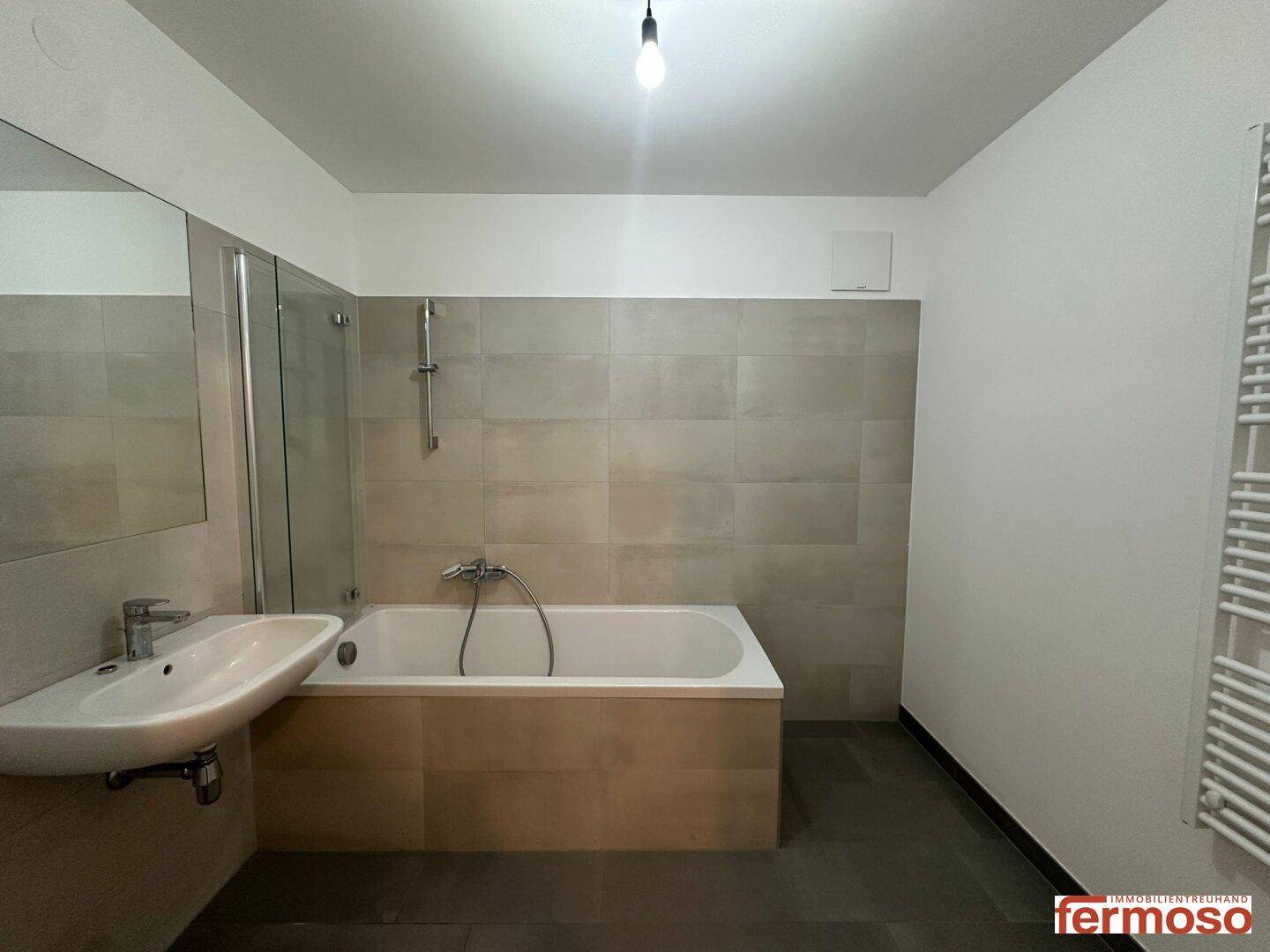 Modernes Badezimmer mit Badewanne, Dusche, Einzelwaschbecken und beheiztem Handtuchhalter.