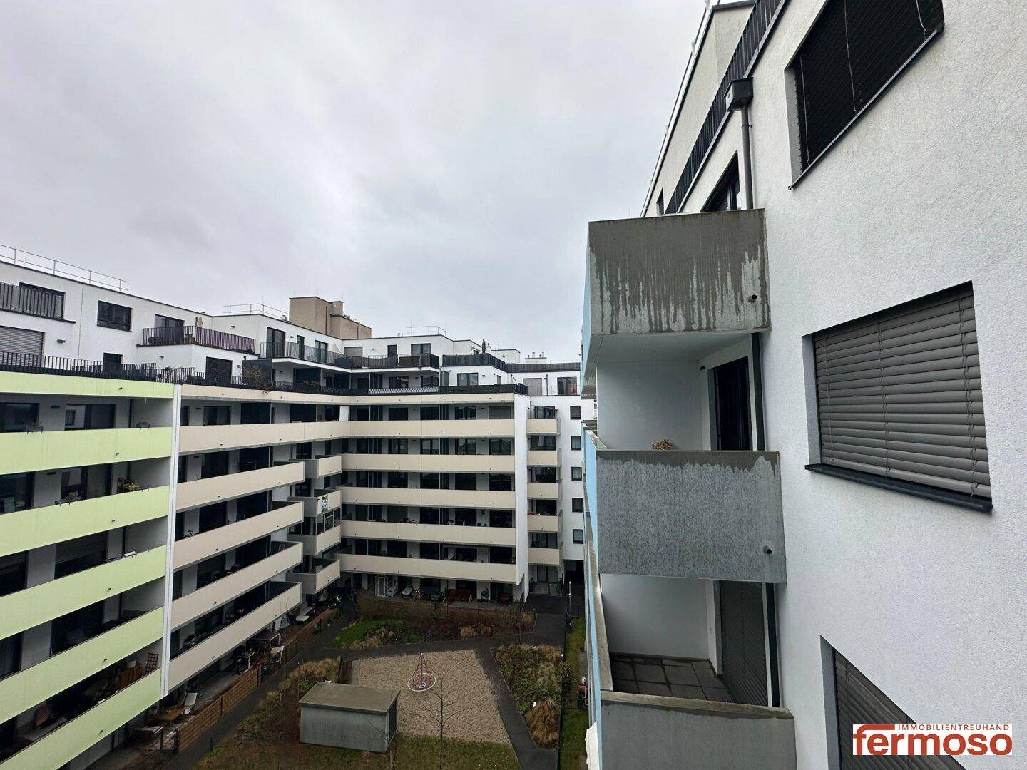 Moderne Wohnanlage mit mehreren Balkonen und einem begrünten Innenhof.