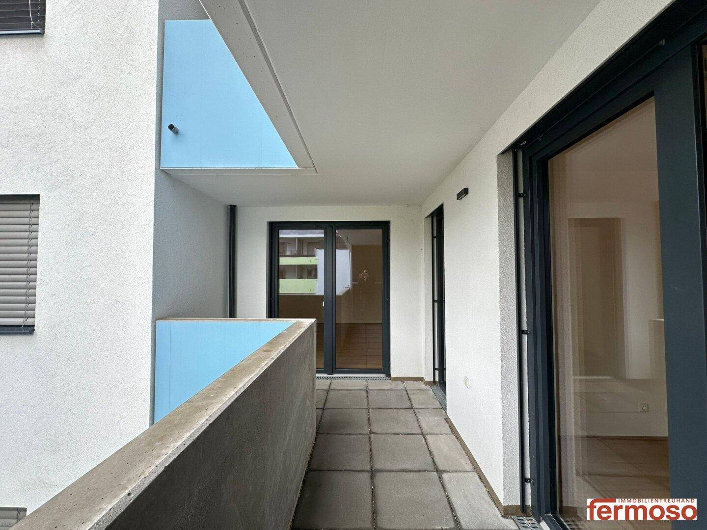 Geräumiger Balkon mit Fliesenboden und Blick auf die umliegenden Gebäude.