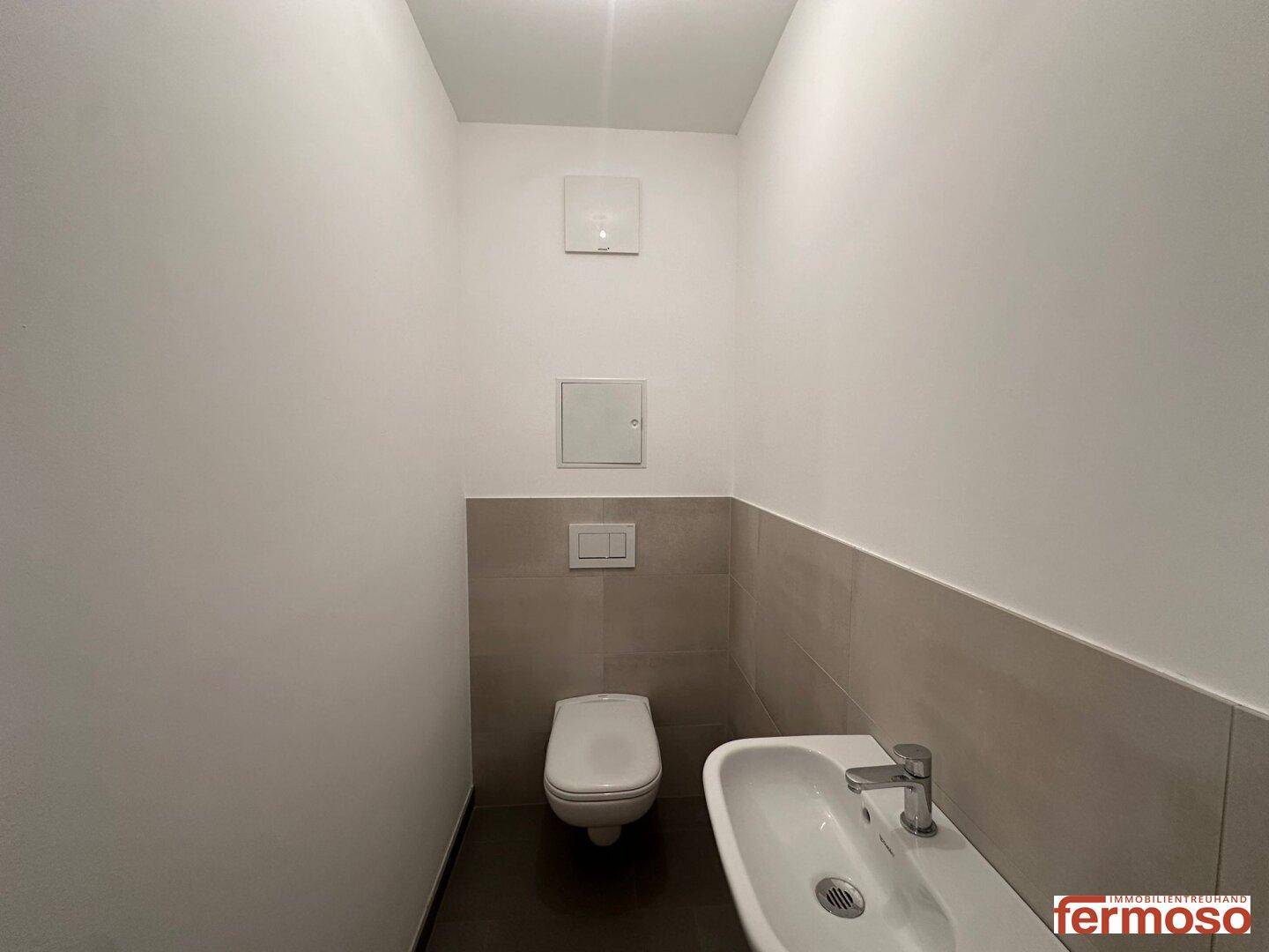 Modernes Gäste-WC mit Wand-WC, Einzelwaschbecken und Fliesenboden.
