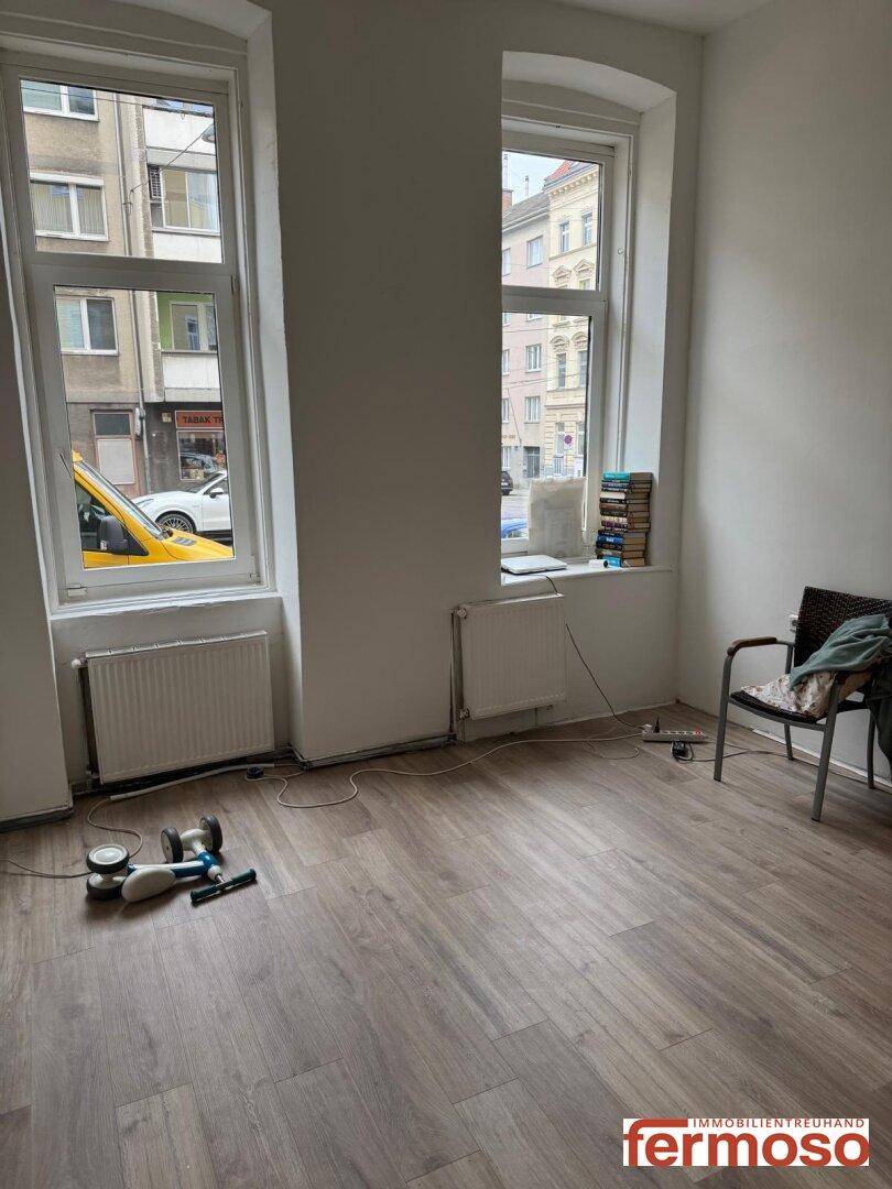 Heller Raum mit großen Fenstern und neuem Laminatboden, bereit zur individuellen Gestaltung und mit Stadtblick.