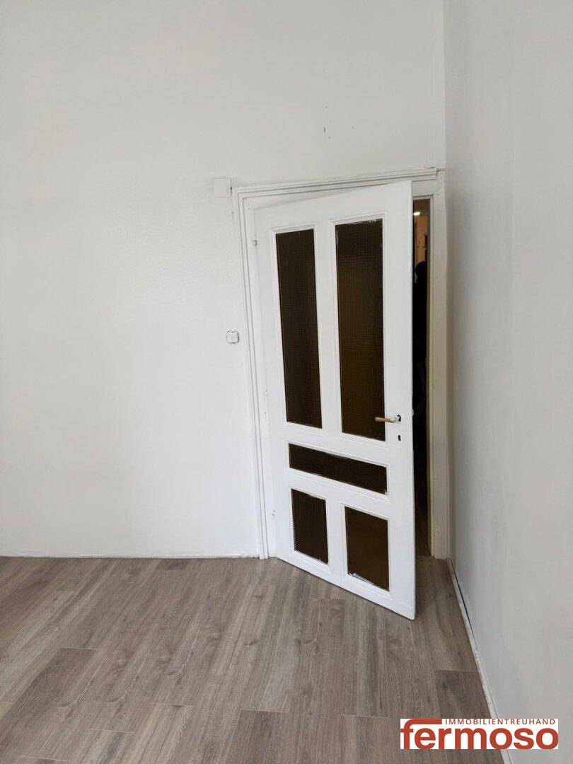 Eine weiße Innentür mit Glaseinsätzen in einem hellen Raum mit Laminatboden, der viel Potenzial bietet.