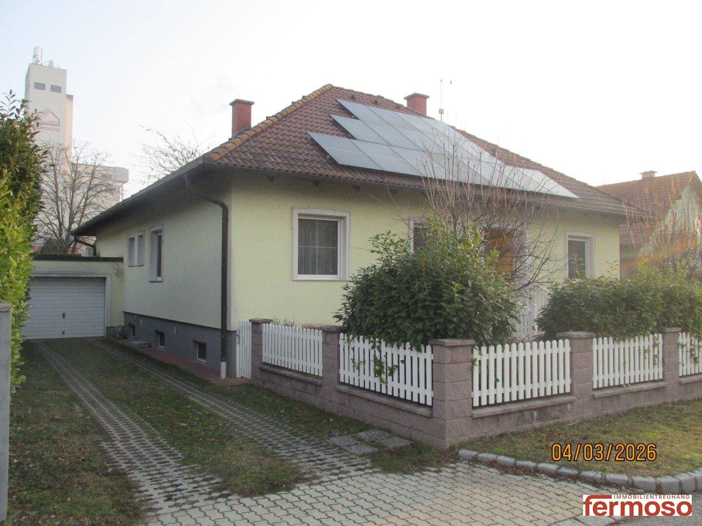 Hausansicht mit Solaranlage, Einfahrt und Garage, umgeben von einem gepflegten Vorgarten.