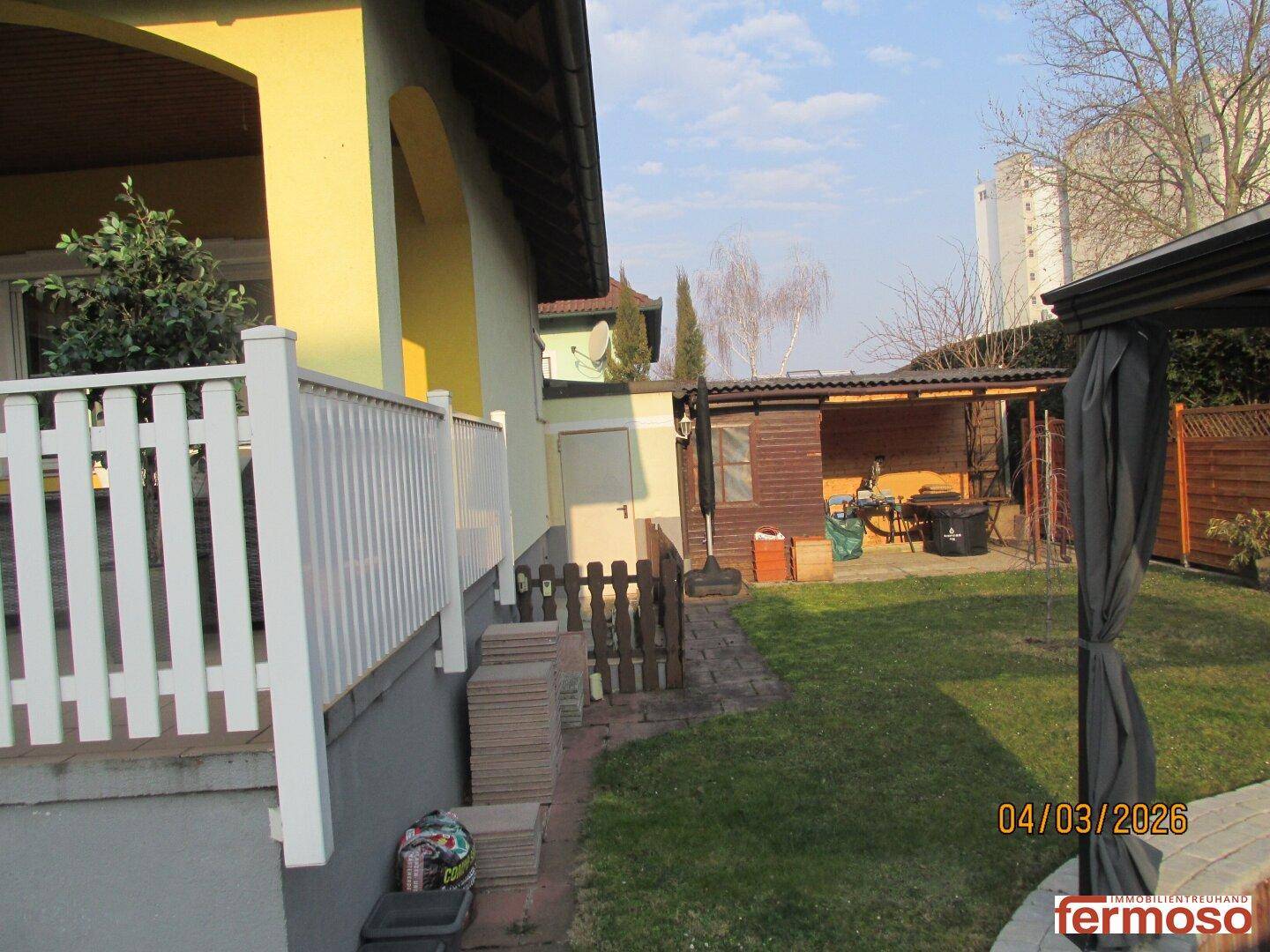 Seitenansicht des Hauses mit Garten, Schuppen und einem weiteren Sitzbereich im Freien.
