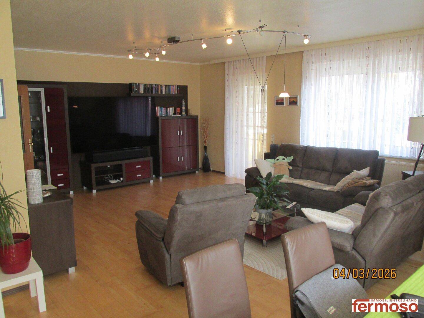 Geräumiges Wohnzimmer mit Laminatboden, bequemen Sofas und großen Fenstern, die viel Licht hereinlassen.