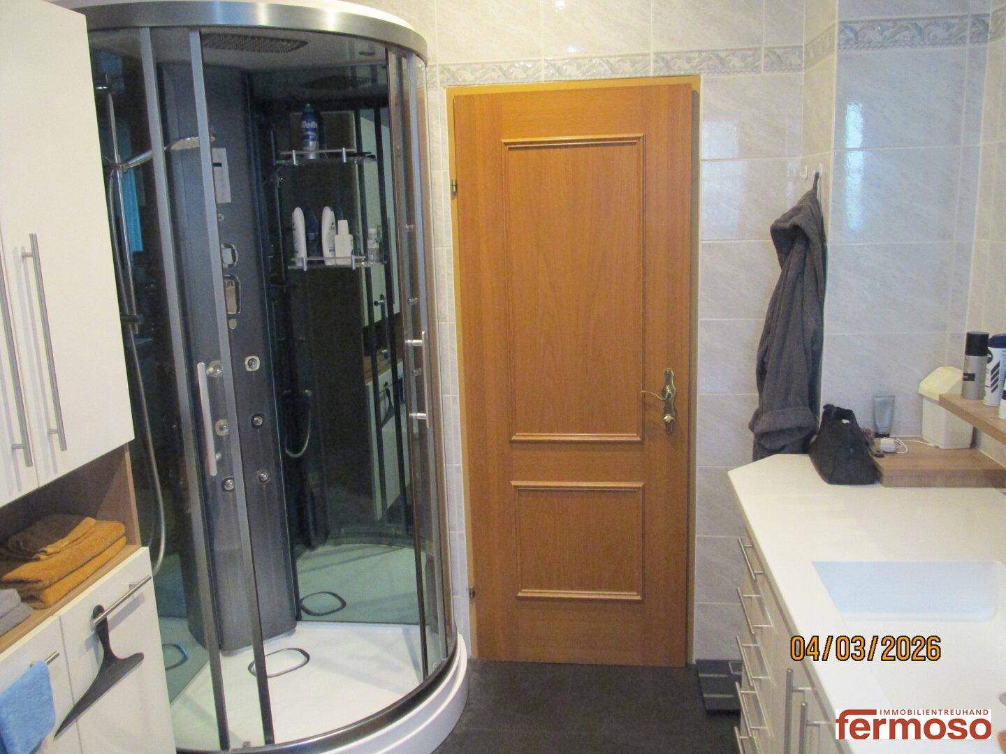 Badezimmer mit moderner Duschkabine, Waschbecken und Stauraum, praktisch und gut ausgestattet.