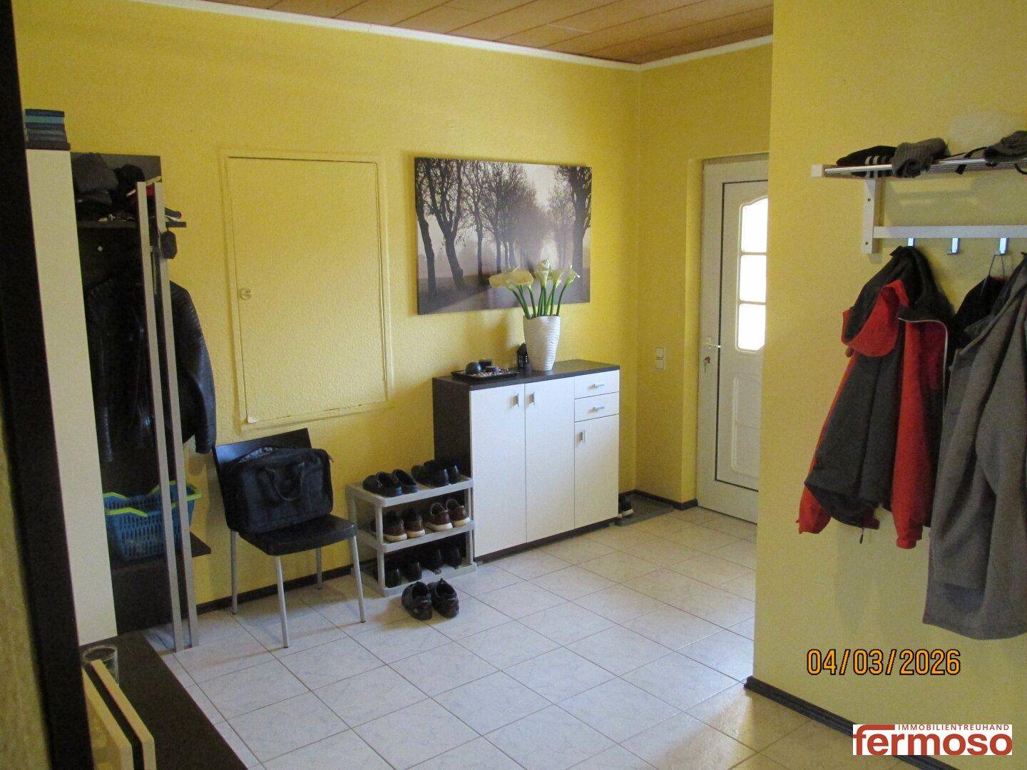 Eingangsbereich mit Fliesenboden, Garderobe und Schuhschrank, hell und einladend gestaltet.