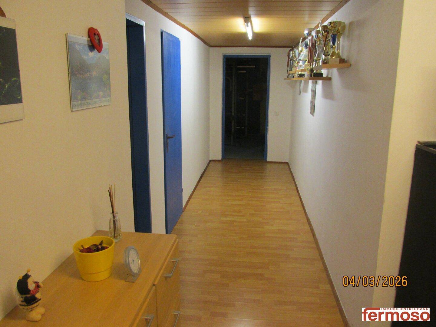 Langer Flur mit Holzdecke, Laminatboden und Regalen mit Trophäen, der zu weiteren Räumen führt.