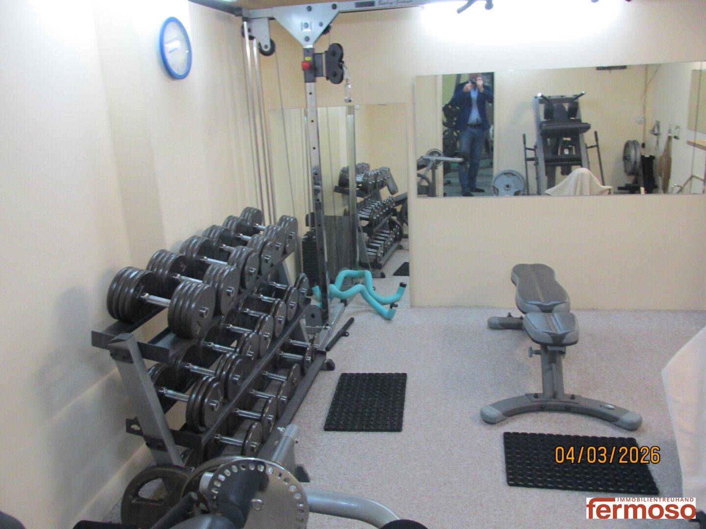 Privater Fitnessraum mit Hanteln, Hantelbank und Spiegeln für das tägliche Training.