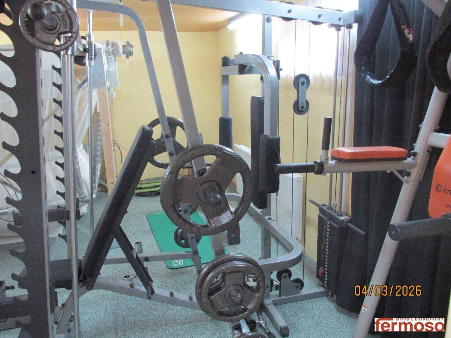 Fitnessraum mit verschiedenen Trainingsgeräten und Hanteln für ein umfassendes Workout.