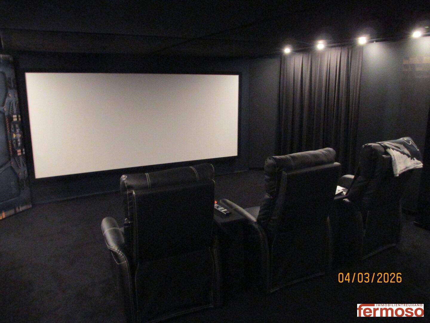 Große Leinwand in einem privaten Heimkino mit bequemen Sitzgelegenheiten und dunkler Einrichtung.