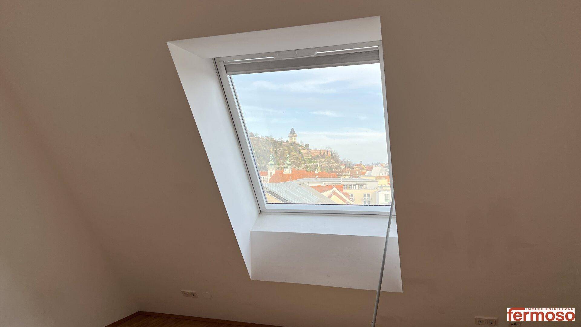 Großes Dachfenster in einem Schlafzimmer, das viel natürliches Licht und eine weite Aussicht bietet.