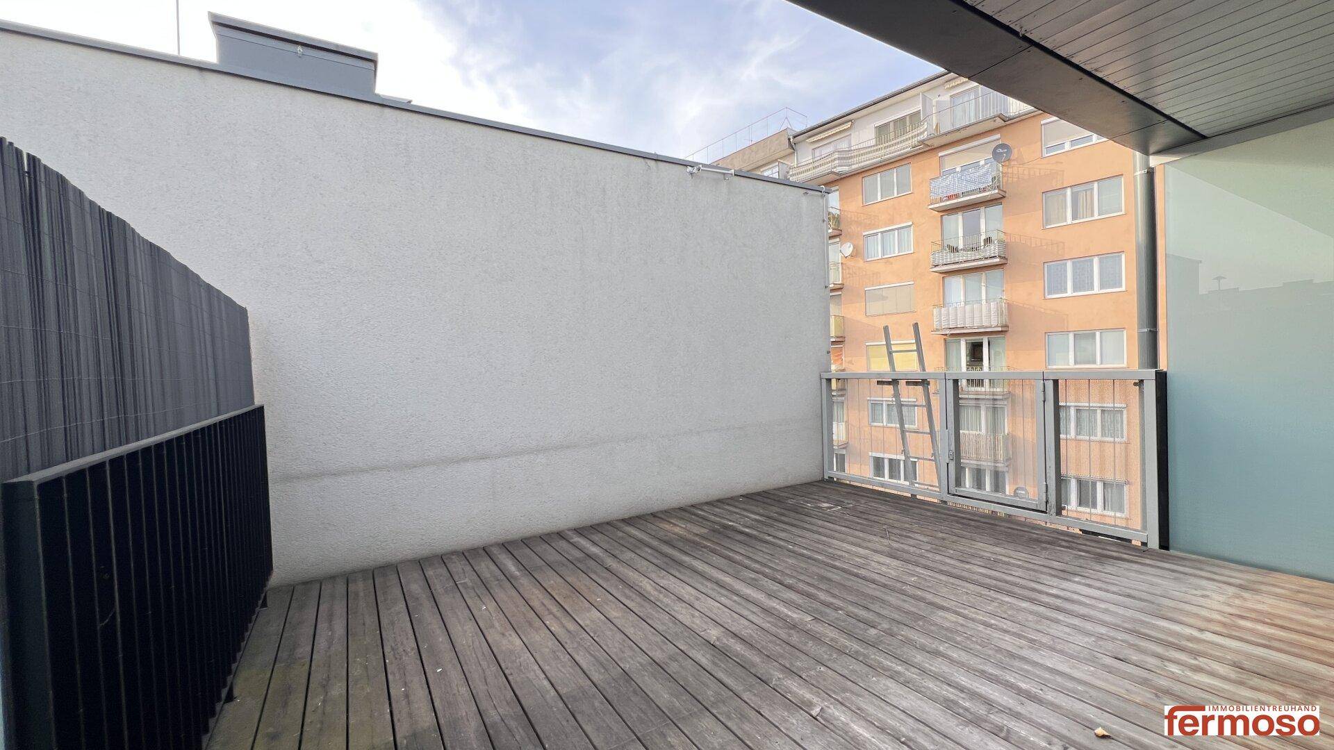 Leere Holzterrasse mit Blick auf die umliegenden Gebäude, bietet viel Platz für individuelle Gestaltung.