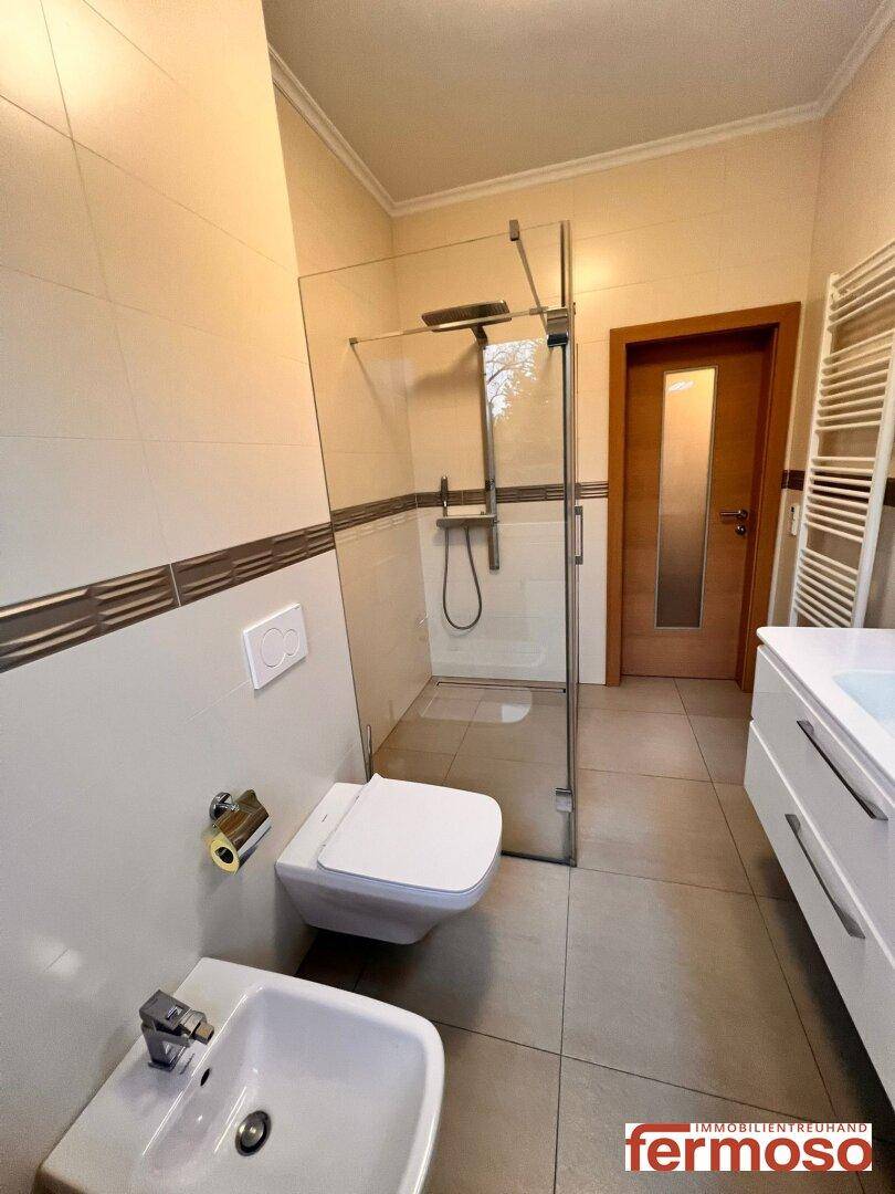 Modernes Badezimmer mit begehbarer Dusche, wandhängendem WC, Bidet und Einzelwaschbecken.