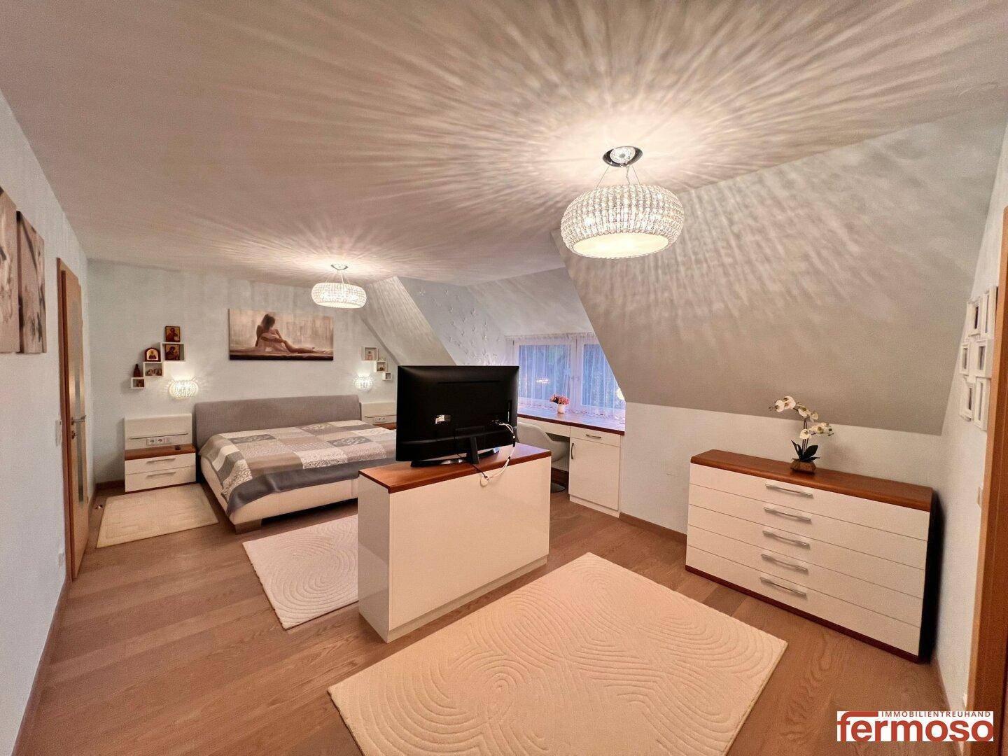 Helles Schlafzimmer im Dachgeschoss mit schrägen Decken und modernem Mobiliar.
