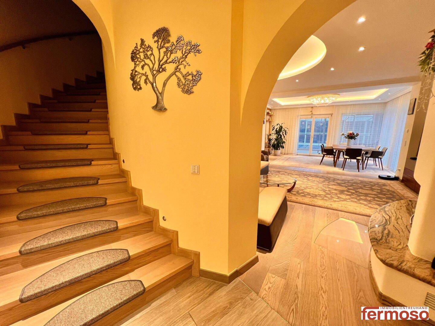 Geschwungene Holztreppe mit dekorativer Wandkunst, die zum hellen Wohnbereich führt.
