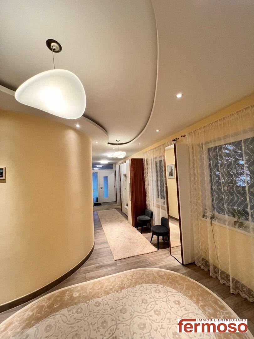 Heller Flur mit geschwungener Wand, Einbaustrahlern und modernem Design.