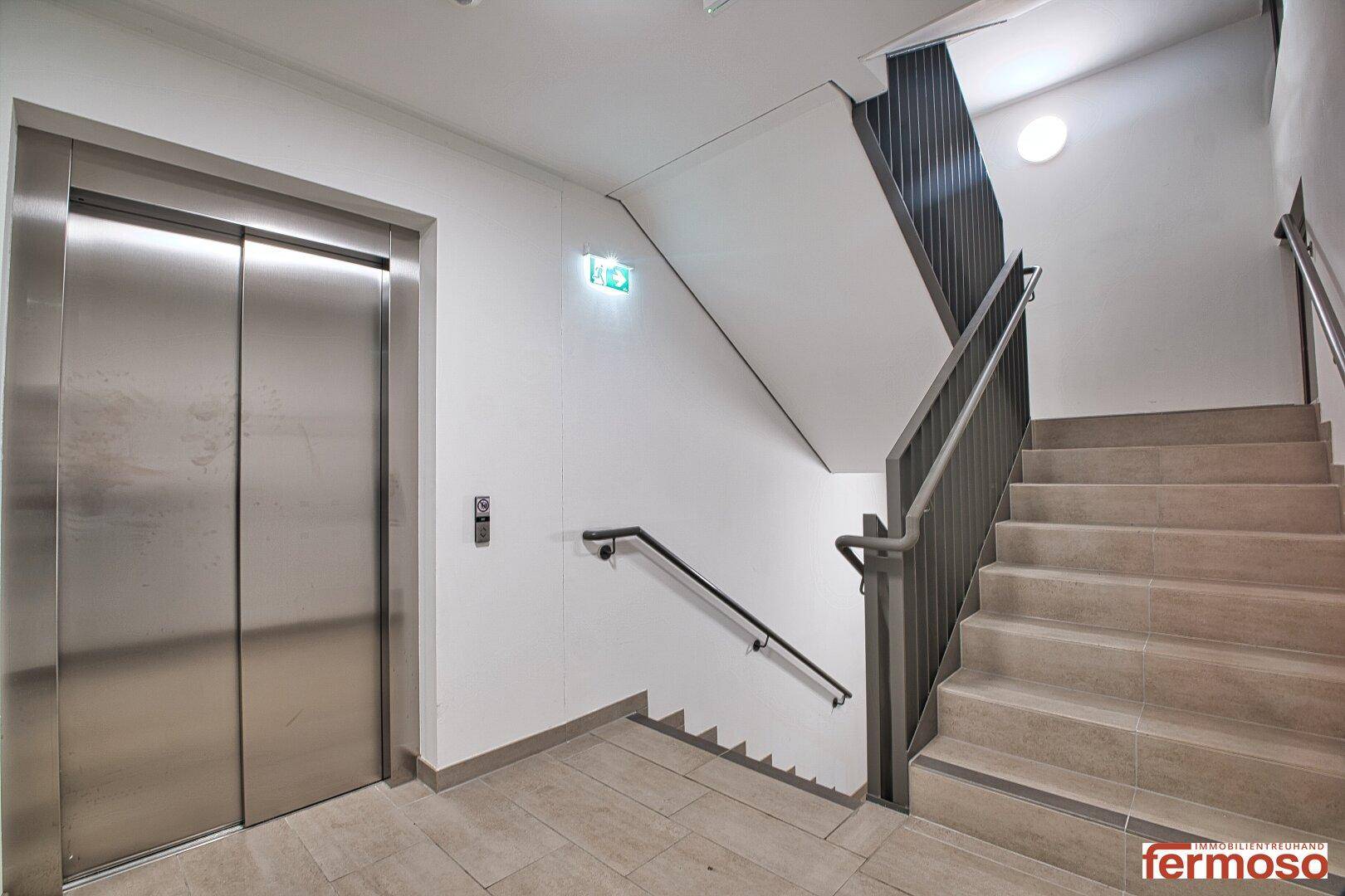 Heller Treppenaufgang und moderner Aufzug in einem Mehrparteienhaus.