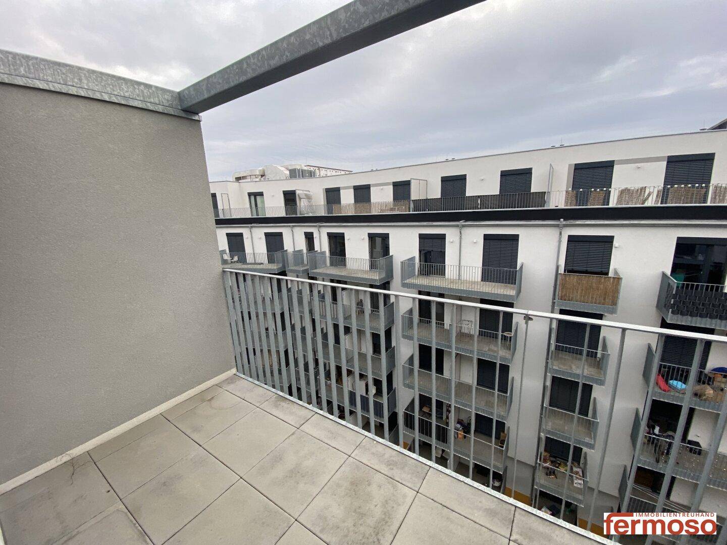 Balkon mit Metallgeländer und Blick auf die Innenhöfe der angrenzenden Wohngebäude.