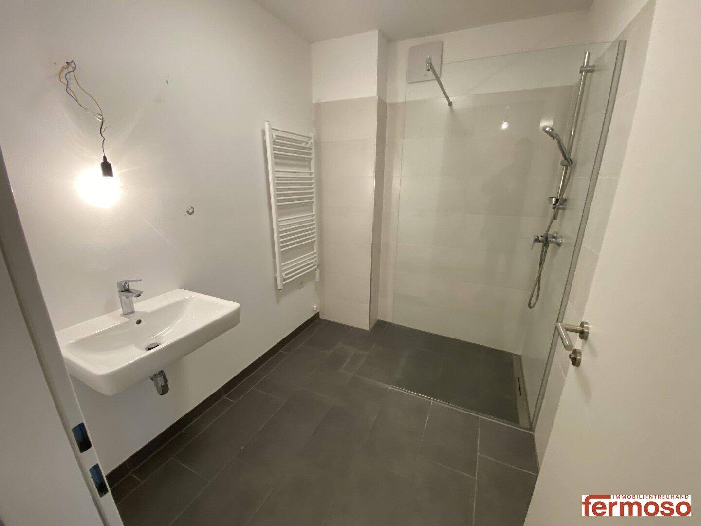 Modernes Badezimmer mit ebenerdiger Dusche, Waschbecken und beheiztem Handtuchhalter.