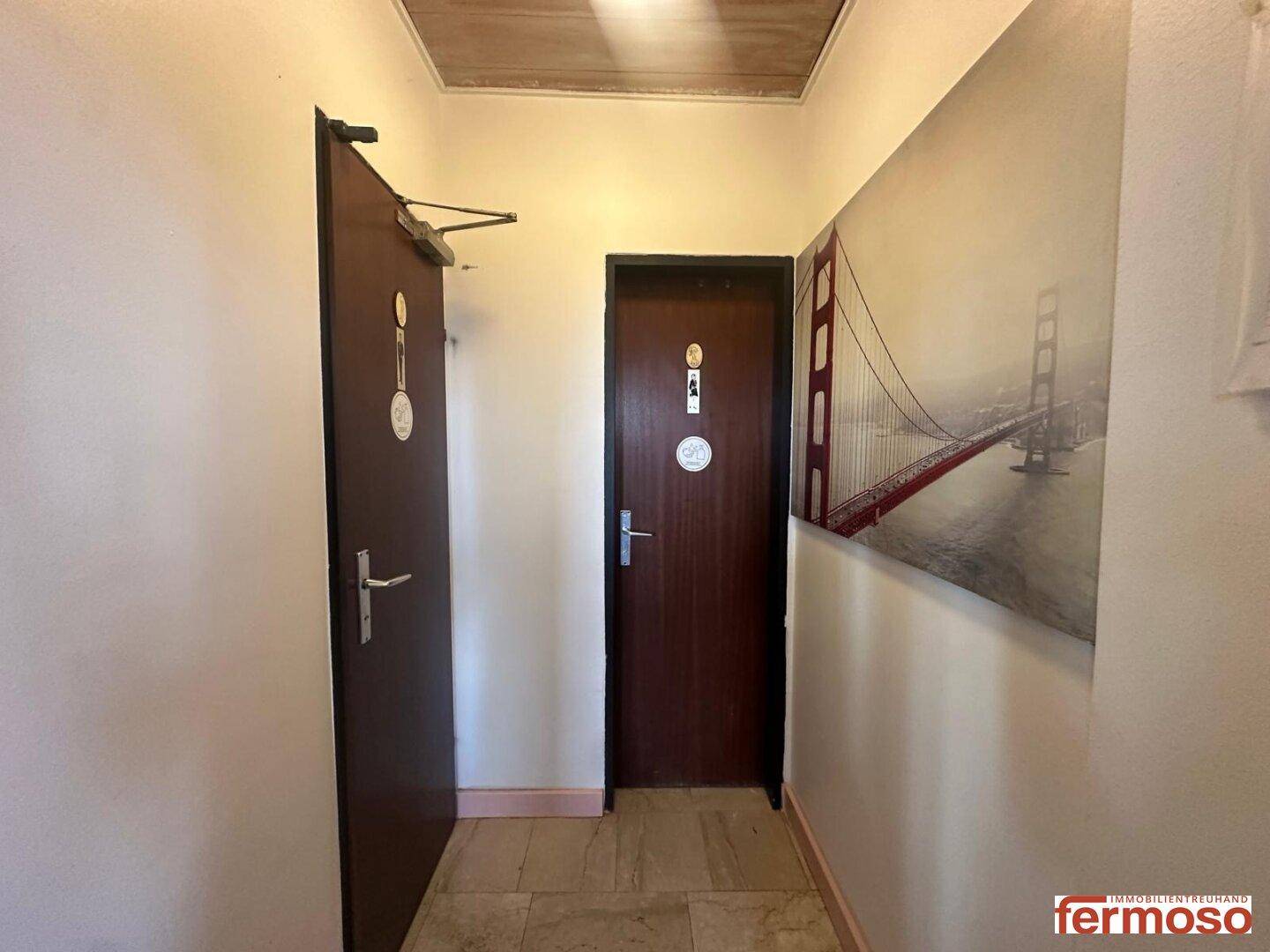 Schmaler Flur mit zwei Holztüren und einem Wandbild der Golden Gate Bridge.
