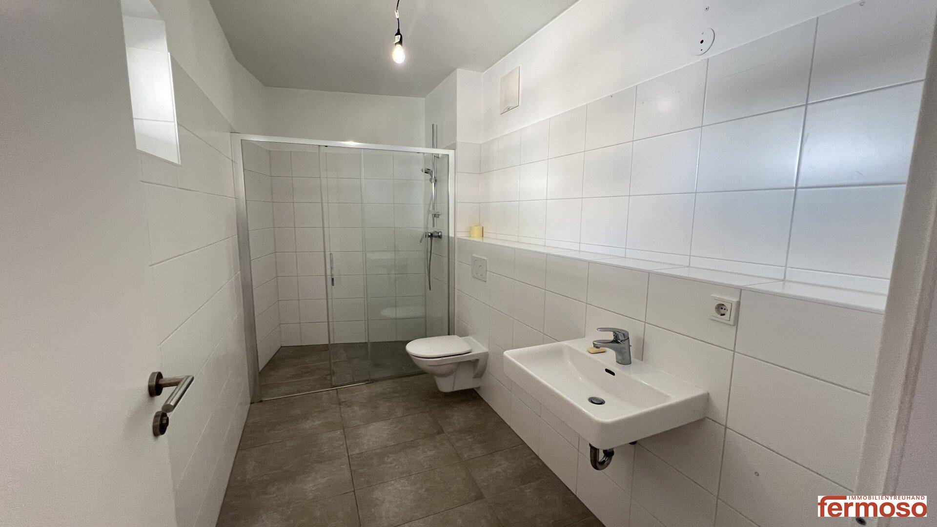 Modernes Badezimmer mit Duschkabine, WC, Waschbecken und weißen Fliesen.