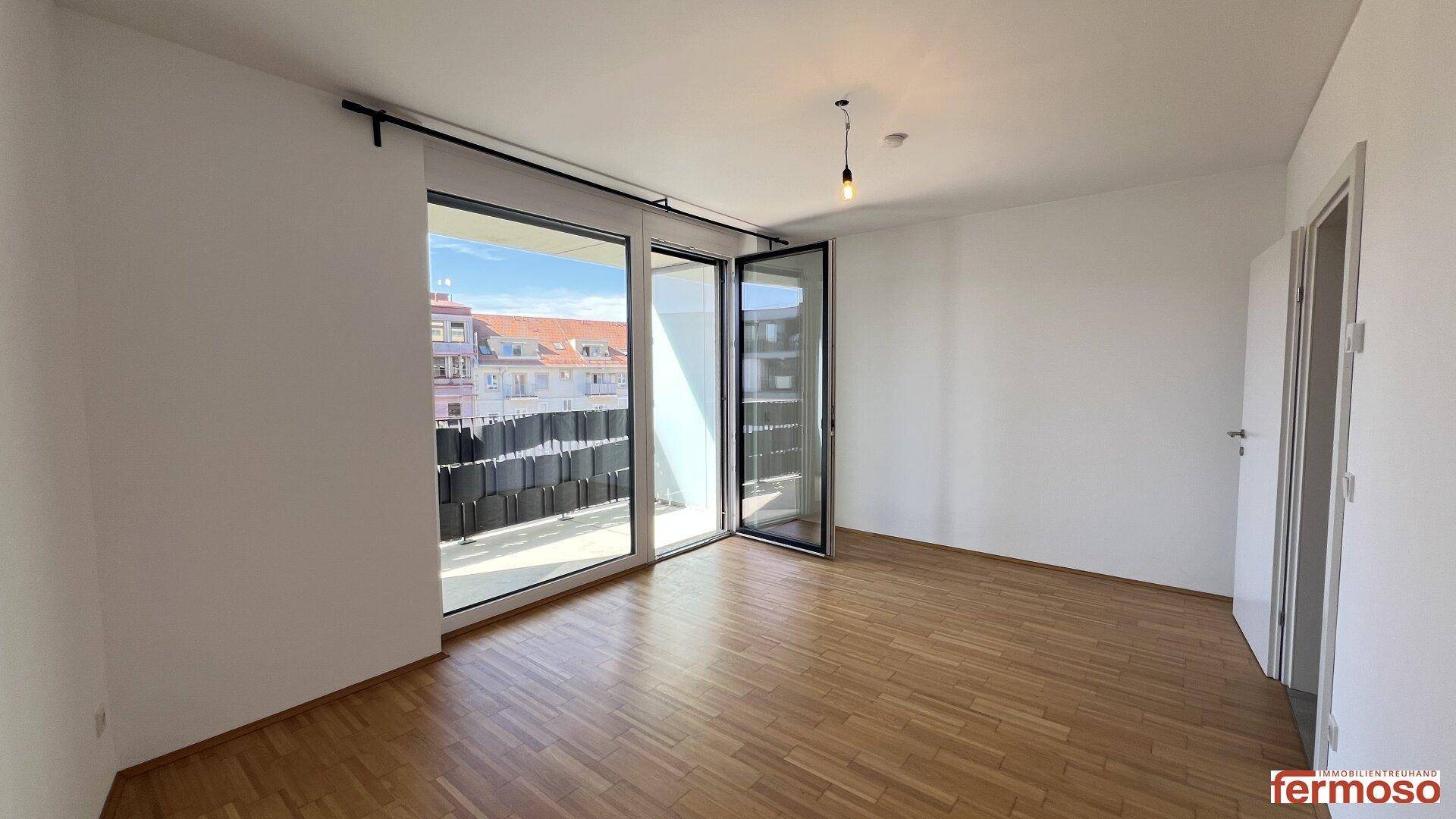Geräumiges Schlafzimmer mit Zugang zum Balkon und hellem Parkettboden.