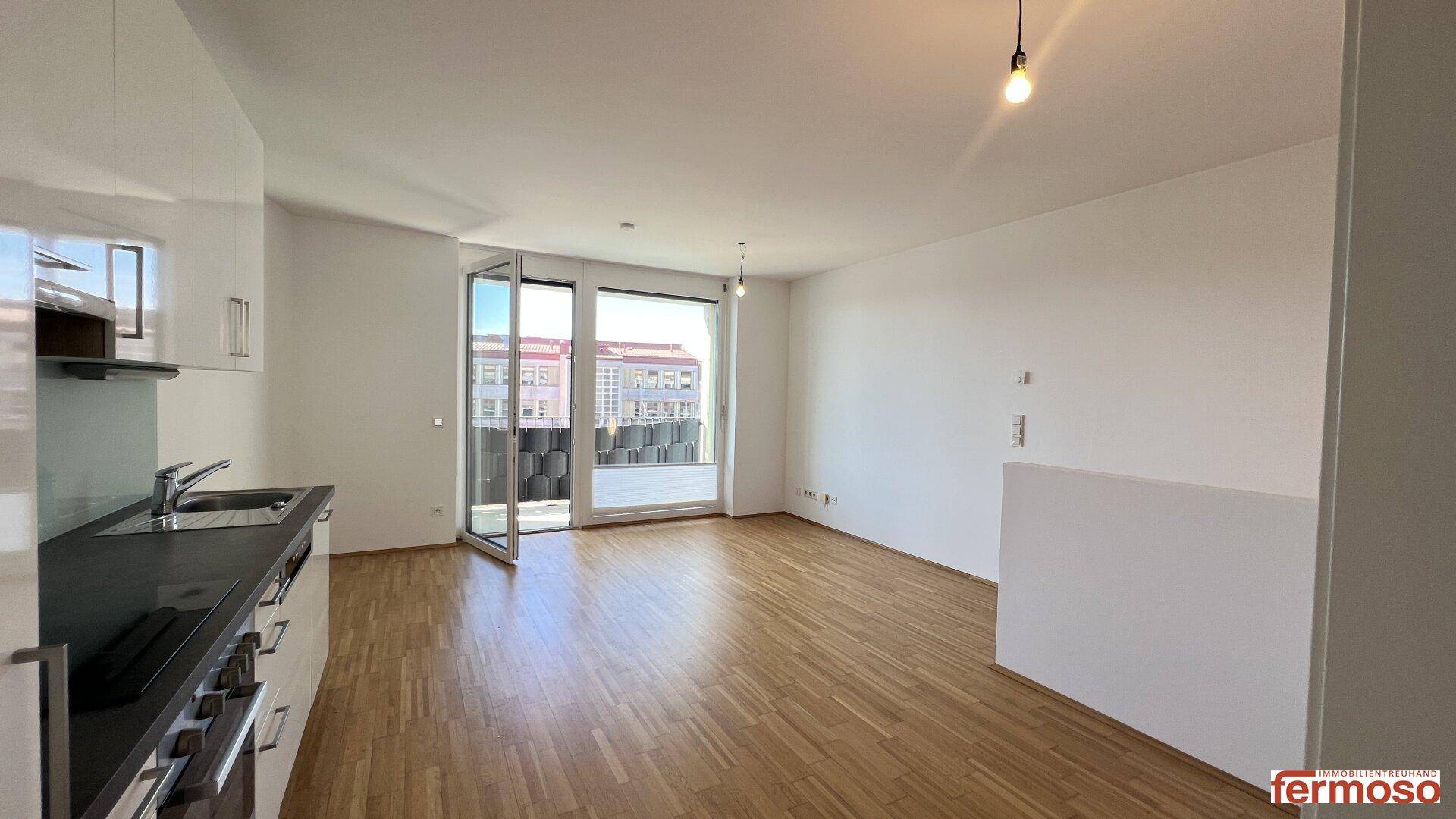 Lichtdurchfluteter Wohnbereich mit Balkonzugang und moderner Küchenzeile.