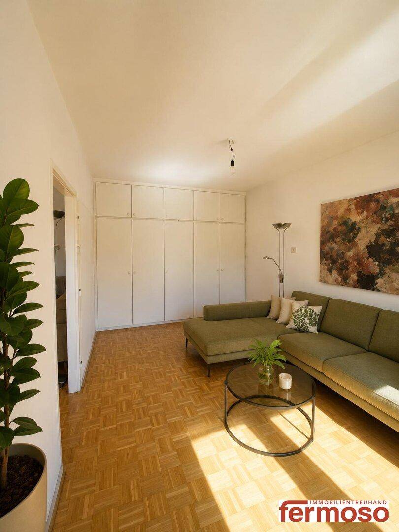 Geräumiges Wohnzimmer mit Parkettboden, Einbauschränken und modernem Ecksofa.