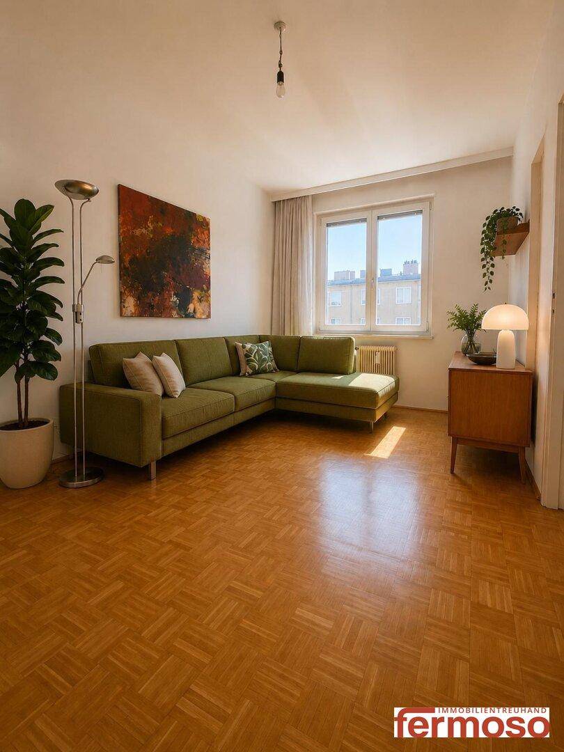 Helles Wohnzimmer mit Parkettboden, grünem Ecksofa und dekorativen Pflanzen.