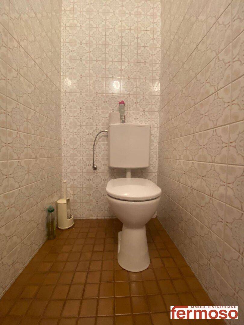 Separate Toilette mit Wandfliesen und gefliestem Boden.