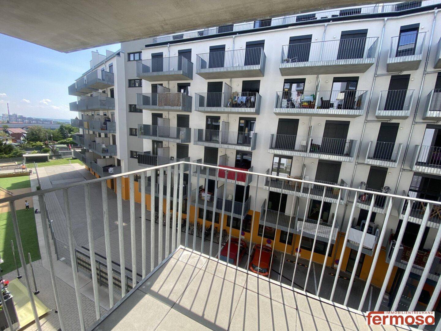Weitläufiger Blick vom Balkon über den Innenhof mit angrenzenden Wohnkomplexen.