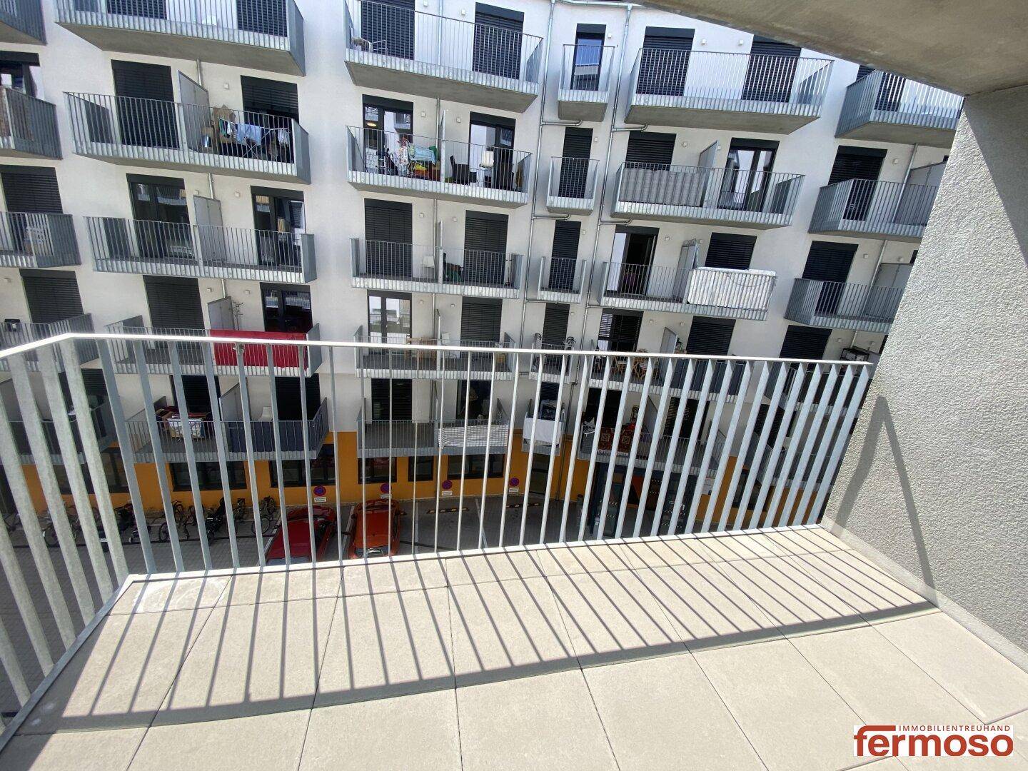 Geräumiger Balkon mit moderner Metallbrüstung und Blick auf die gegenüberliegenden Gebäude.