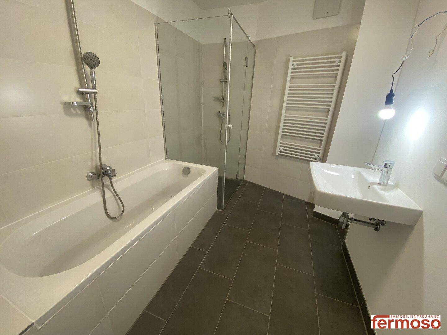 Modernes Badezimmer mit Badewanne, Duschkabine und beheiztem Handtuchhalter.