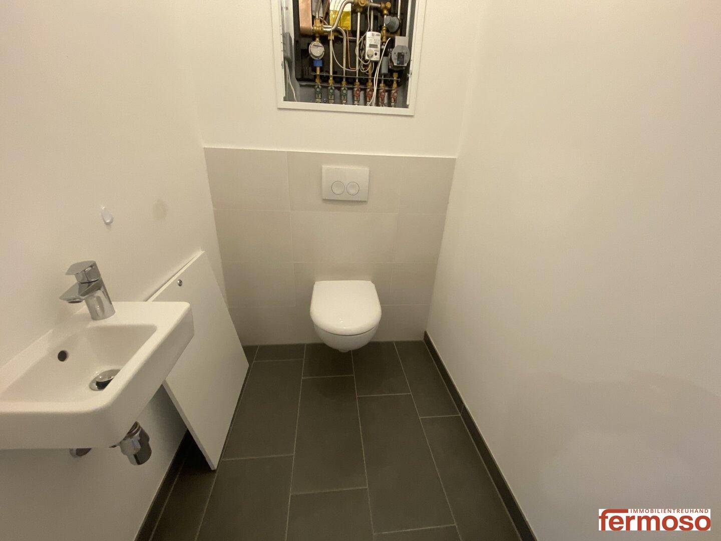 Separates WC mit wandhängender Toilette und kleinem Waschbecken, funktional und modern.