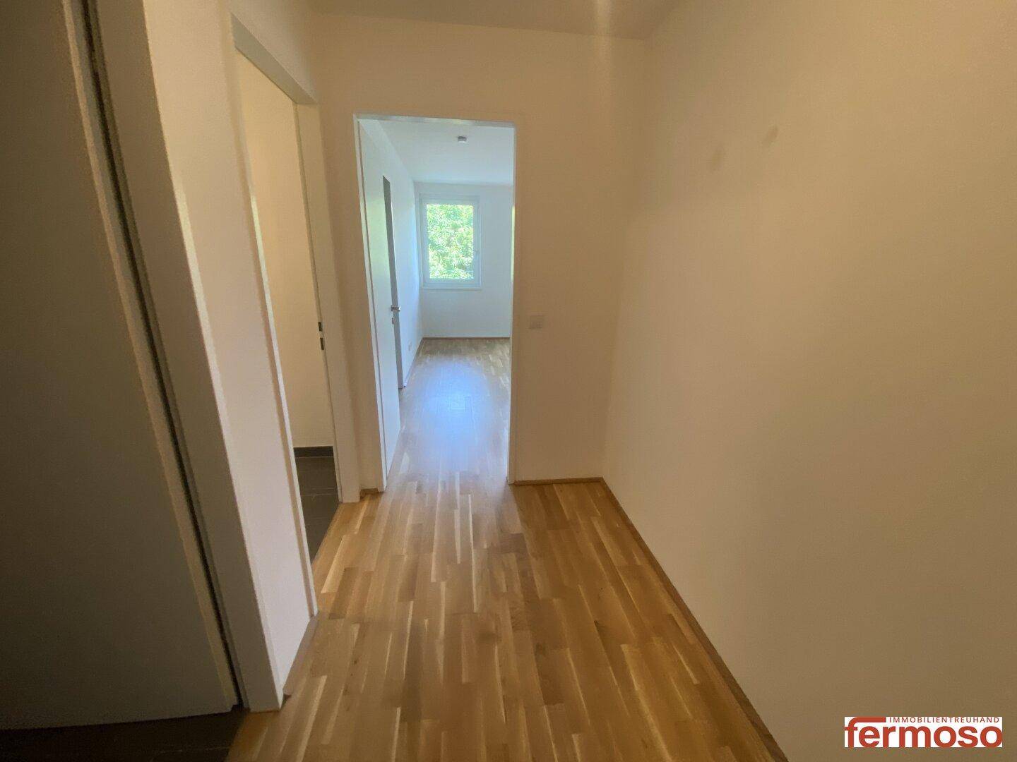 Heller Flur mit Parkettboden, der zu den verschiedenen Zimmern der Wohnung führt.