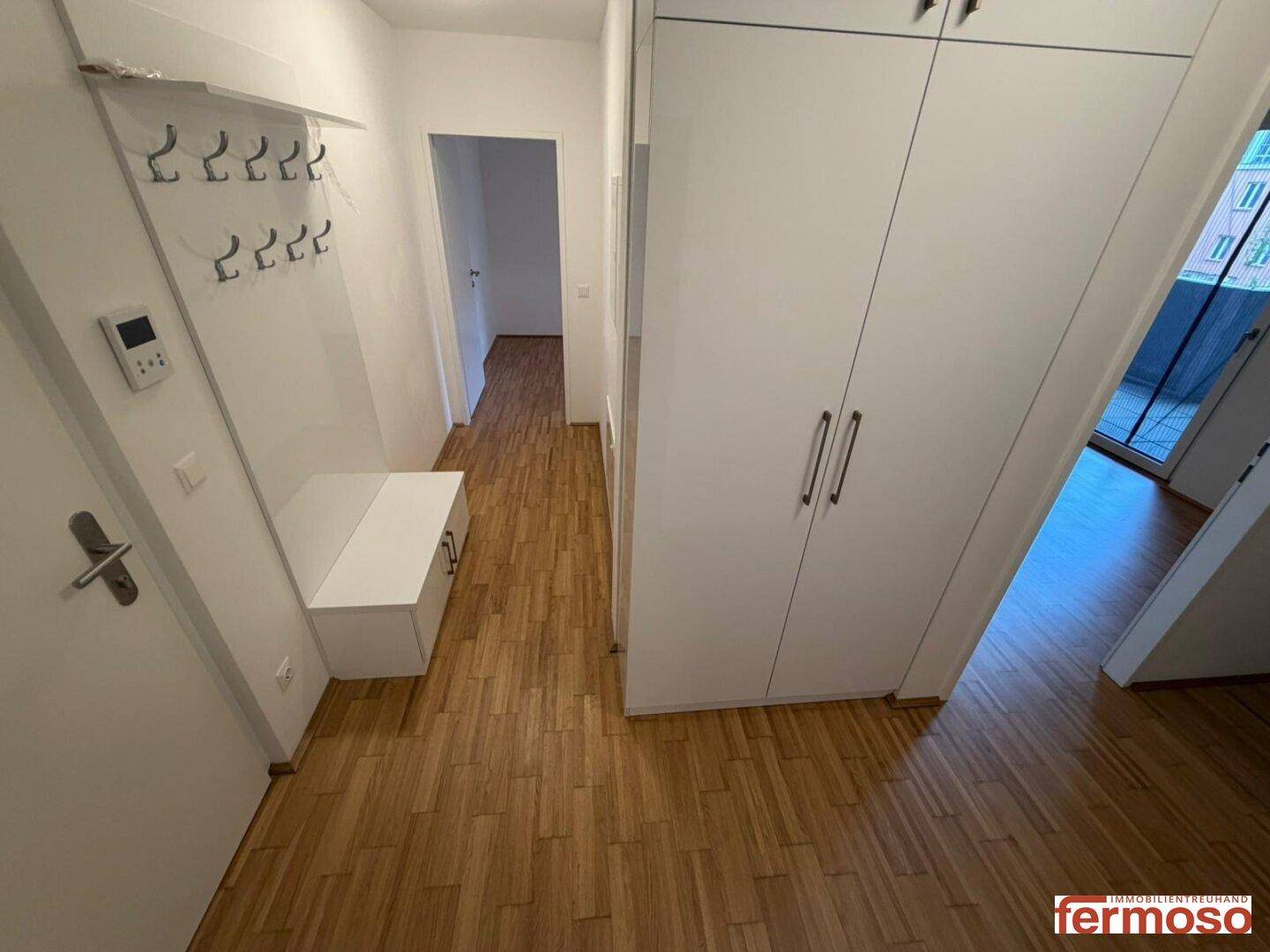 Heller Flur mit Holzboden, Garderobe und praktischem Einbauschrank für Stauraum.