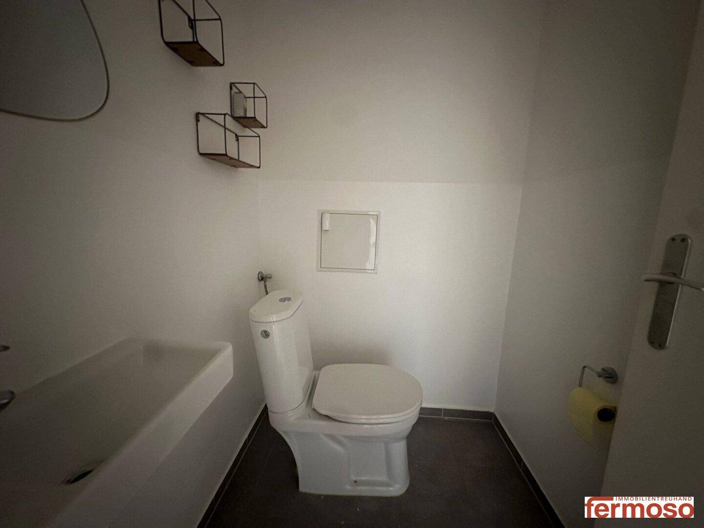 Modernes Gäste-WC mit wandmontierter Toilette und stilvollem Waschbecken.
