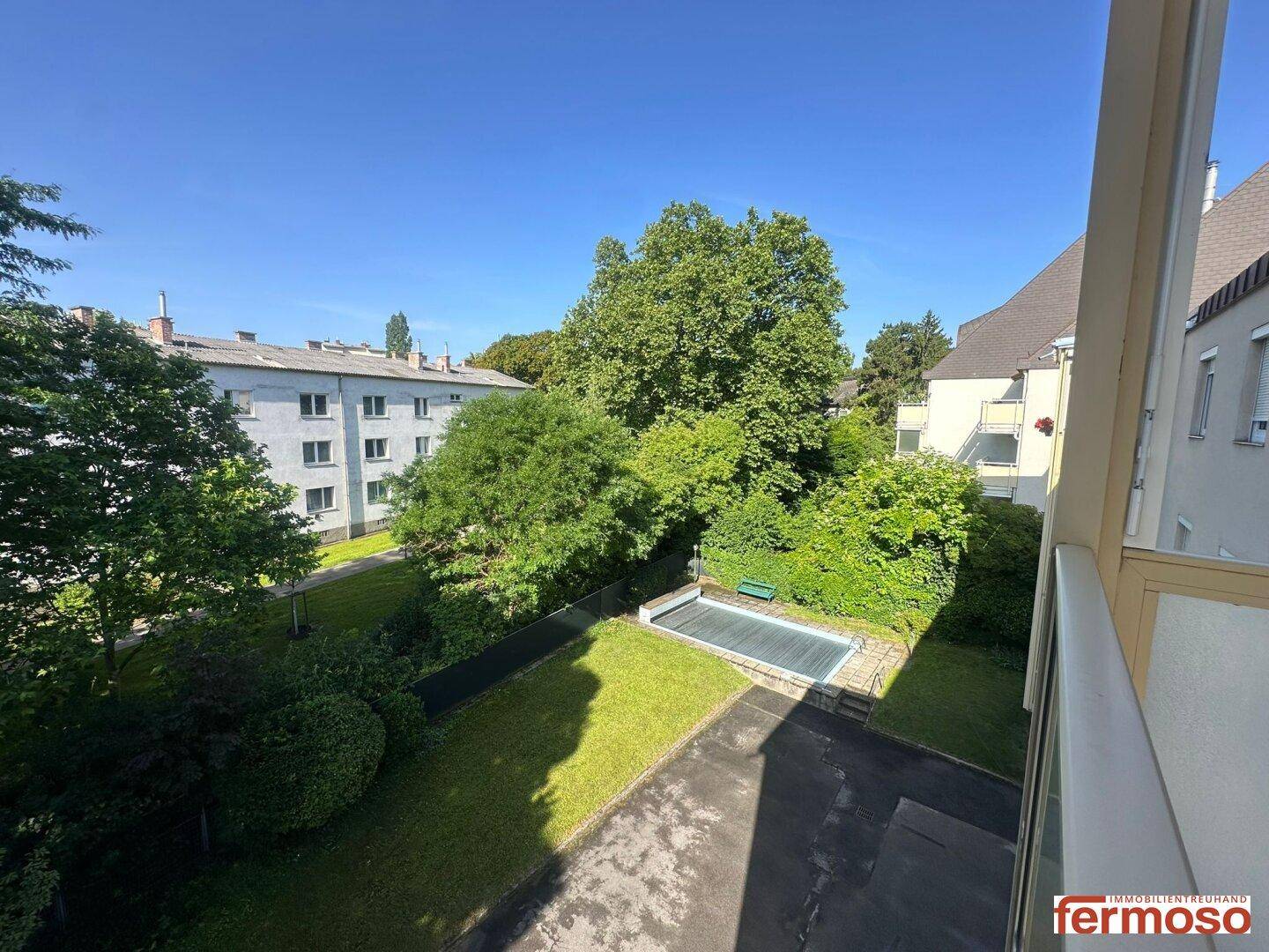 Gemeinschaftsgarten mit Rasenfläche, Bäumen und einem kleinen Außenpool.