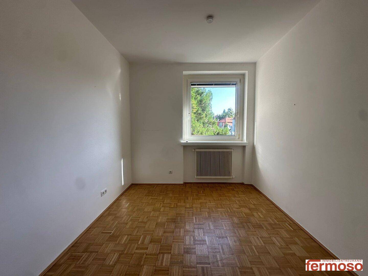Ruhiges Zimmer mit Parkettboden und Fenster, ideal als Kinder- oder Gästezimmer.