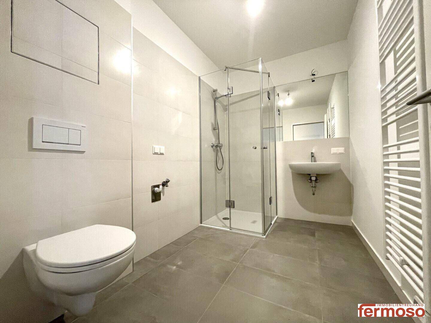 Modernes Badezimmer mit begehbarer Dusche, Wand-WC, Einzelwaschbecken und beheiztem Handtuchhalter.