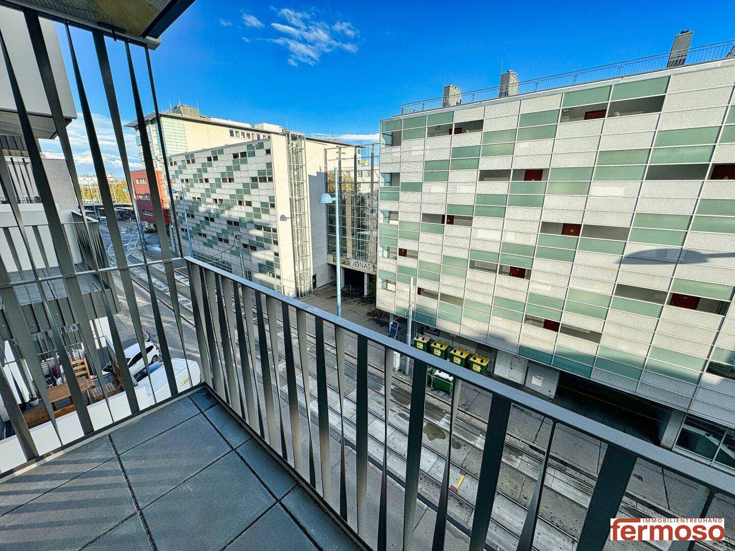 Balkon mit Blick auf die Straße und moderne Gebäude in der Umgebung.