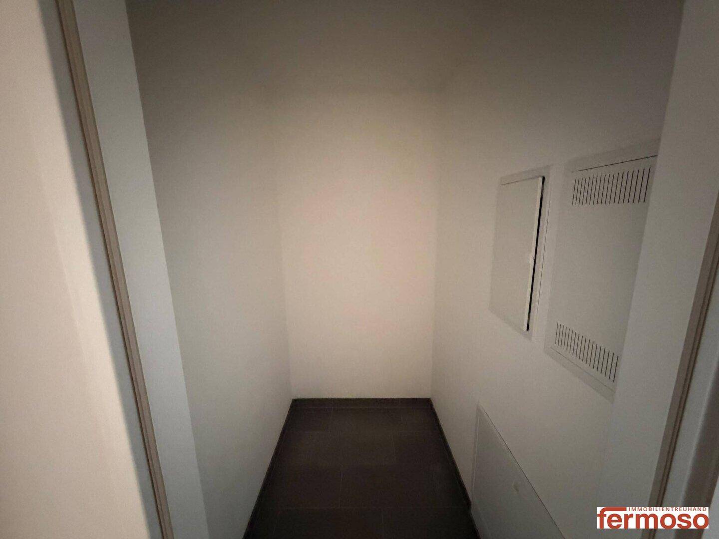 Praktischer Abstellraum mit dunklem Fliesenboden, ideal für zusätzlichen Stauraum.