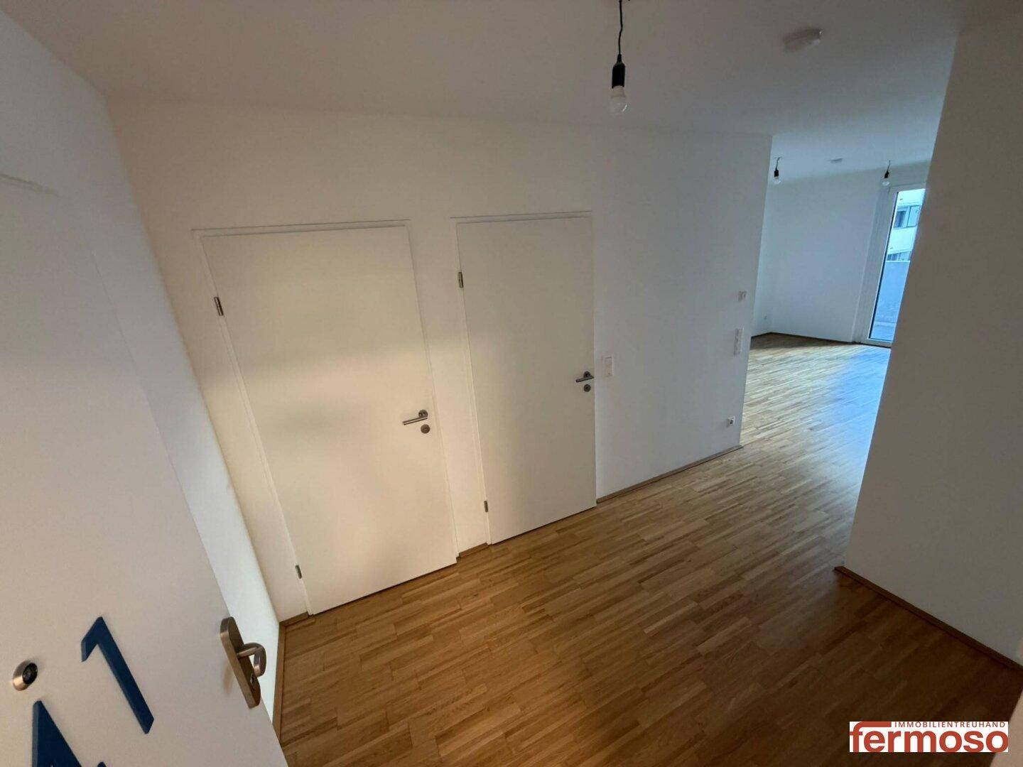 Heller Flur mit Holzboden und mehreren Türen, die zu den verschiedenen Räumen führen.