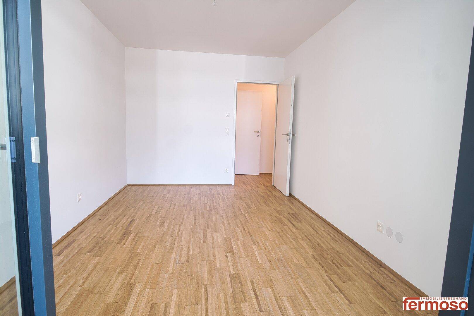 Geräumiger, heller Raum mit Holzboden und weiß gestrichenen Wänden, bereit zum Einrichten.