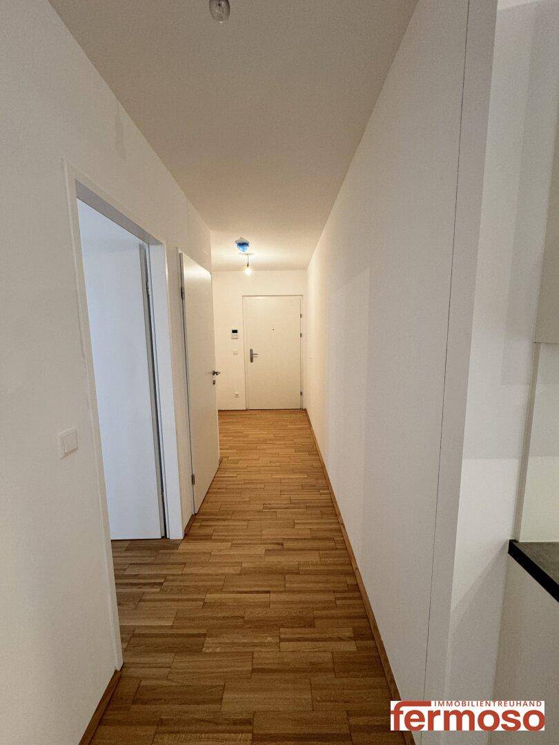 Langer Flur mit hellem Parkettboden, der zu verschiedenen Räumen der Wohnung führt.